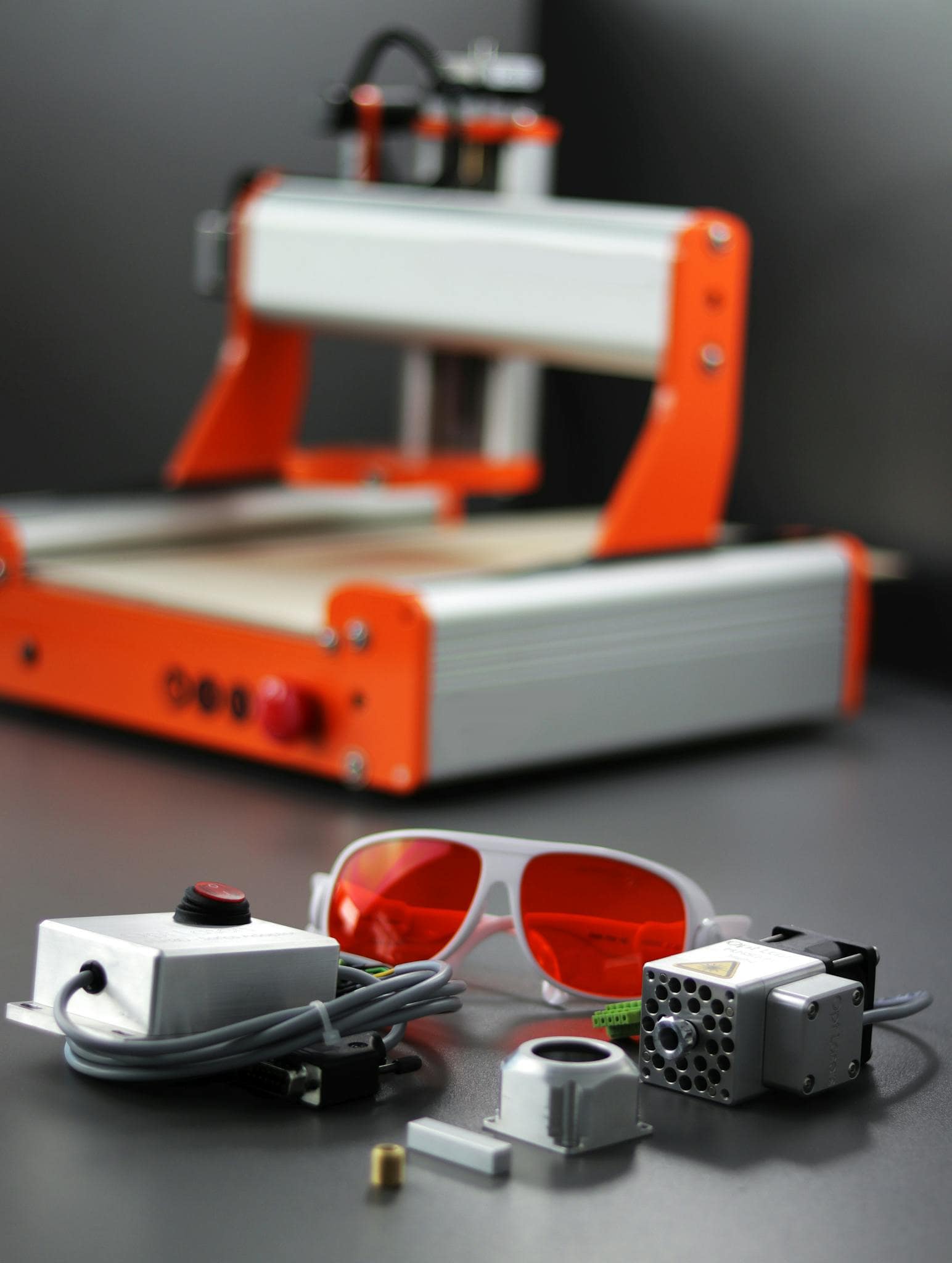 Close-up of a desktop CNC laser engraver with safety goggles and various attachments.